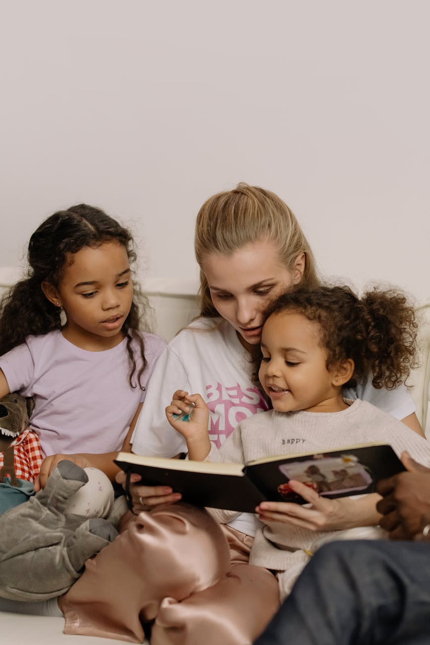 photograph of a mother reading a book with her daughters