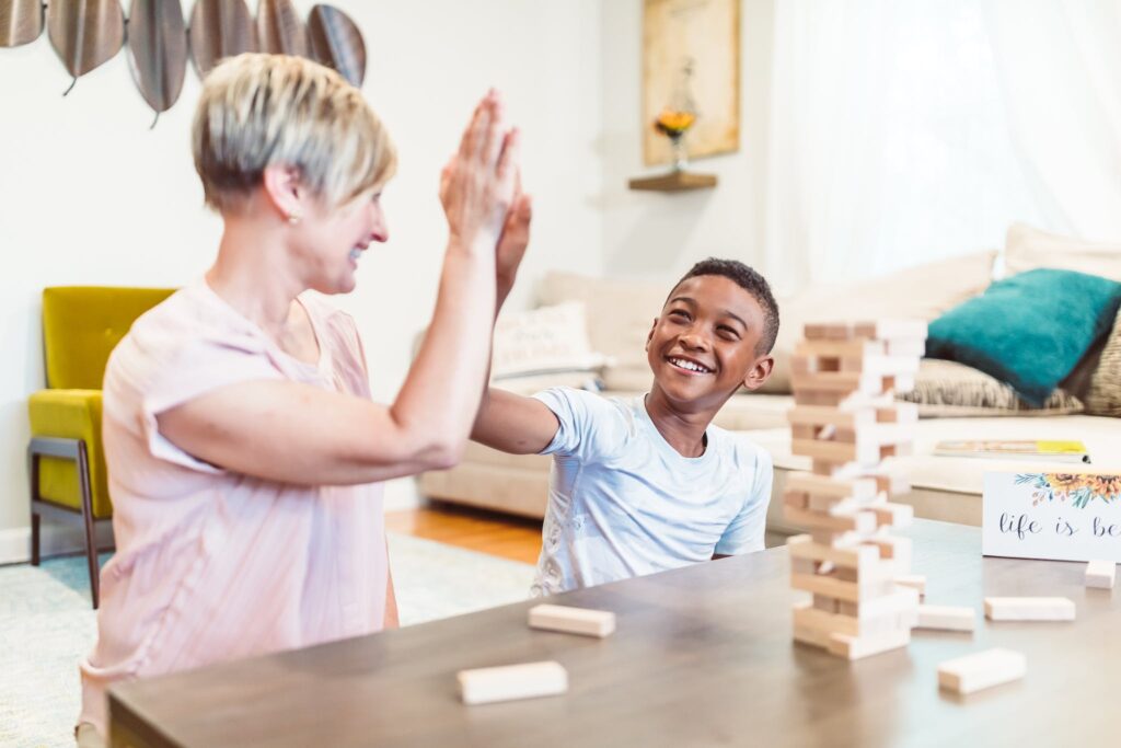 A Boy and a Woman Sitting at a Table with Building Blocks Doing a High Five